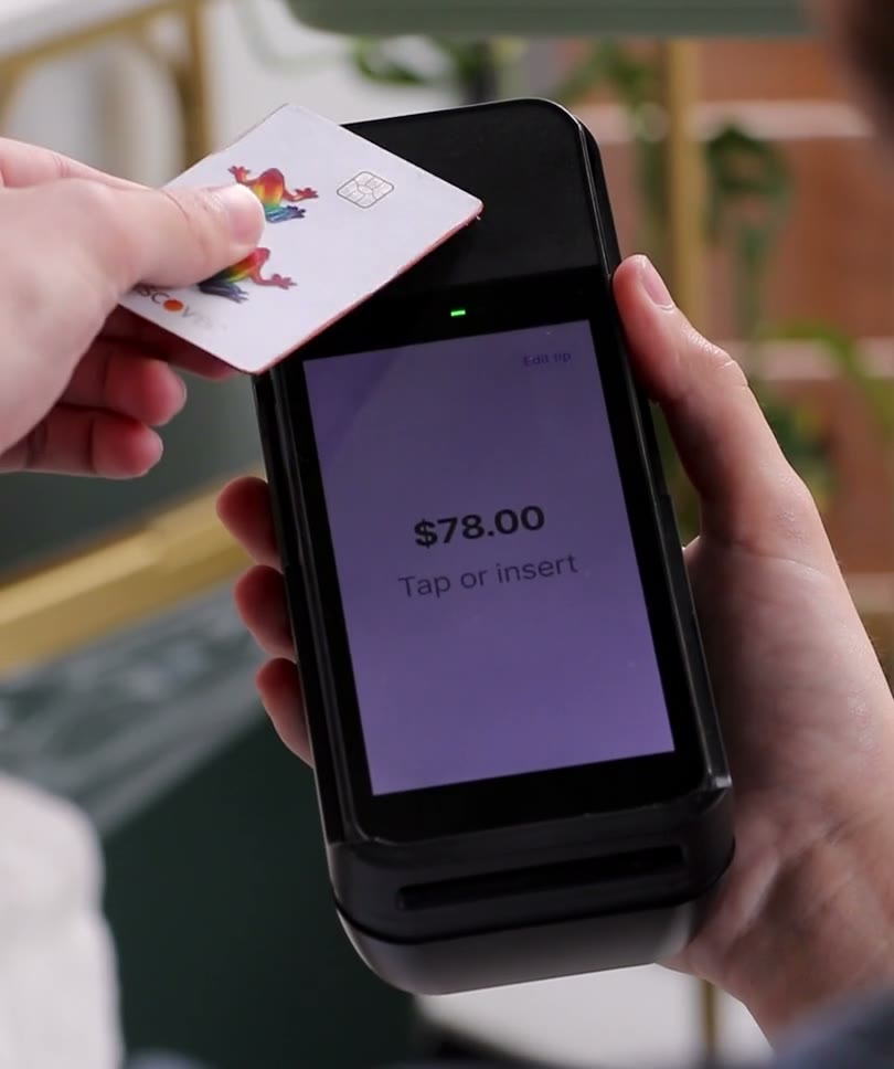 Close-up of a card tapping a card reader. The reader's screen shows $78.00 and Tap or insert, then changes to Processing.